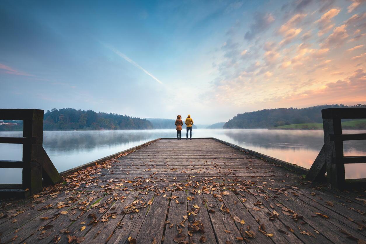 Young couple standing on the jetty and watching sunrise