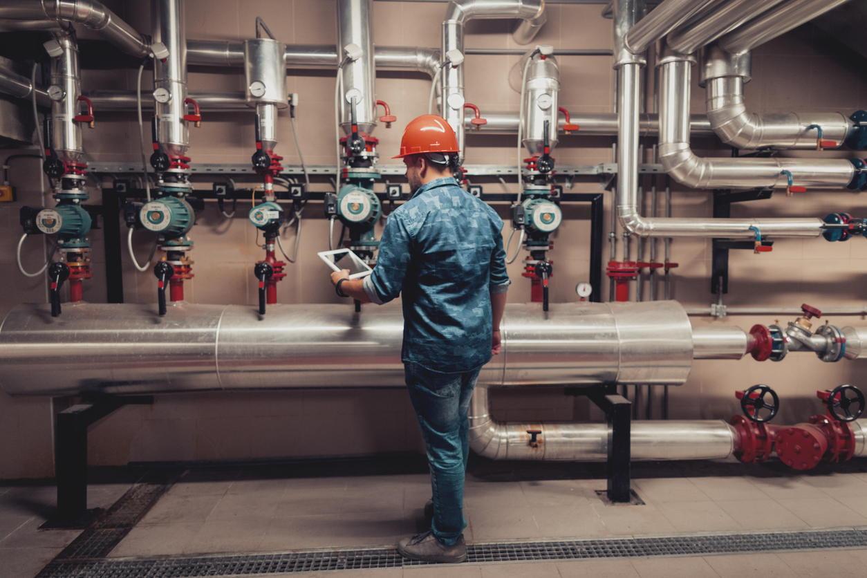 Stationary engineer at work with pipes and gauges